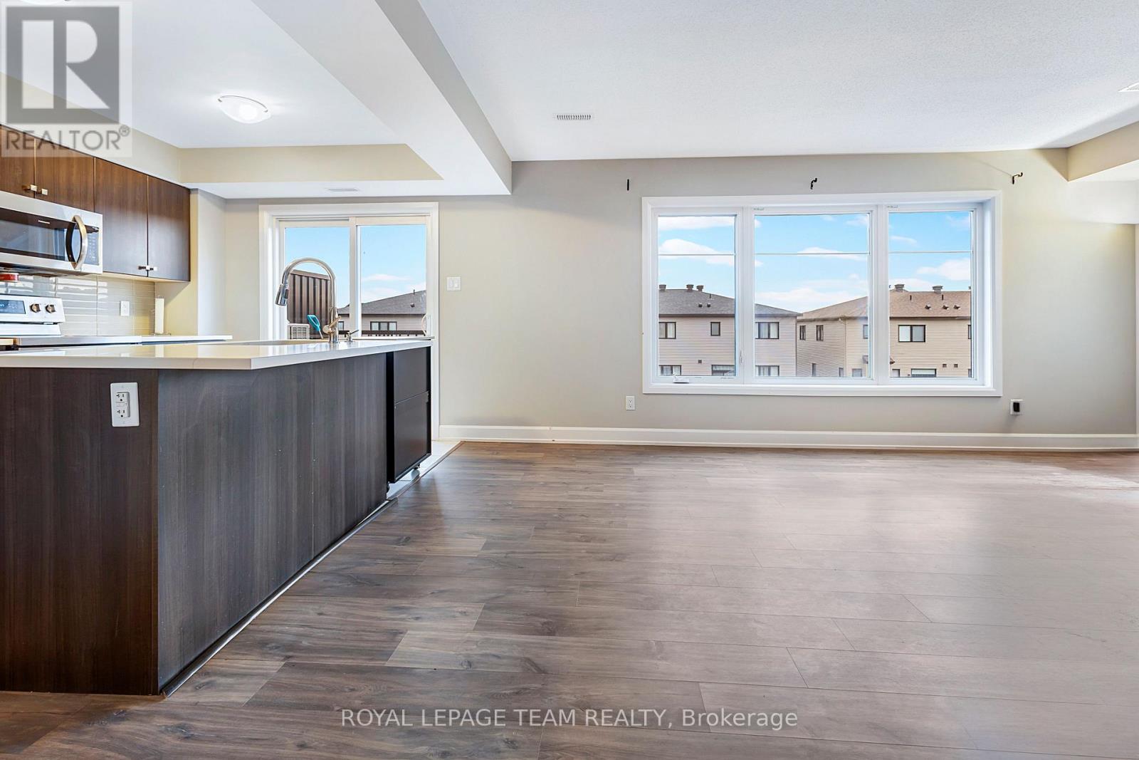 A spacious room with a large window and a view of houses outside.