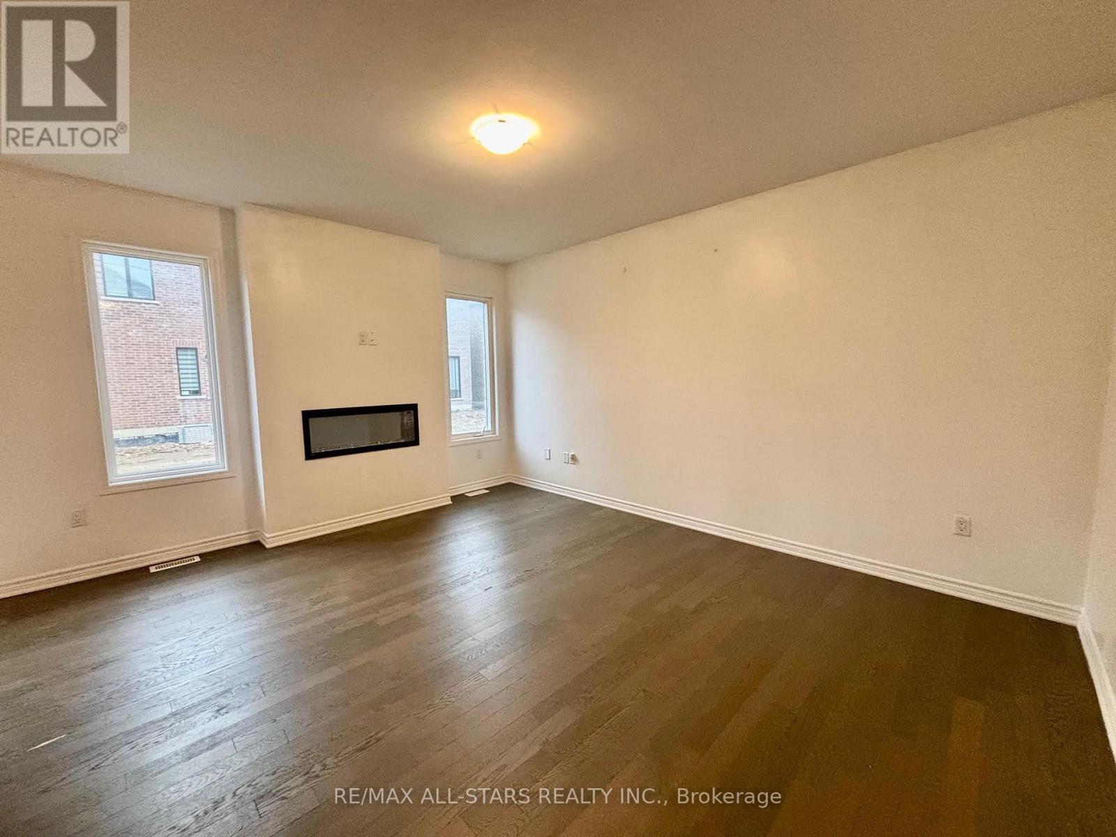 A spacious room with a fireplace and wood flooring.