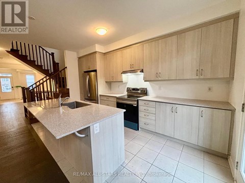 A kitchen with a staircase leading to the upper floor.