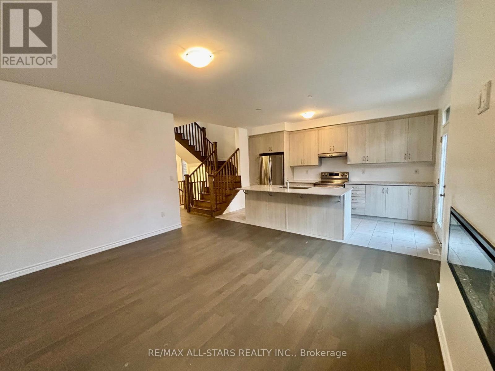 A spacious living room with a staircase leading to the upper floor.