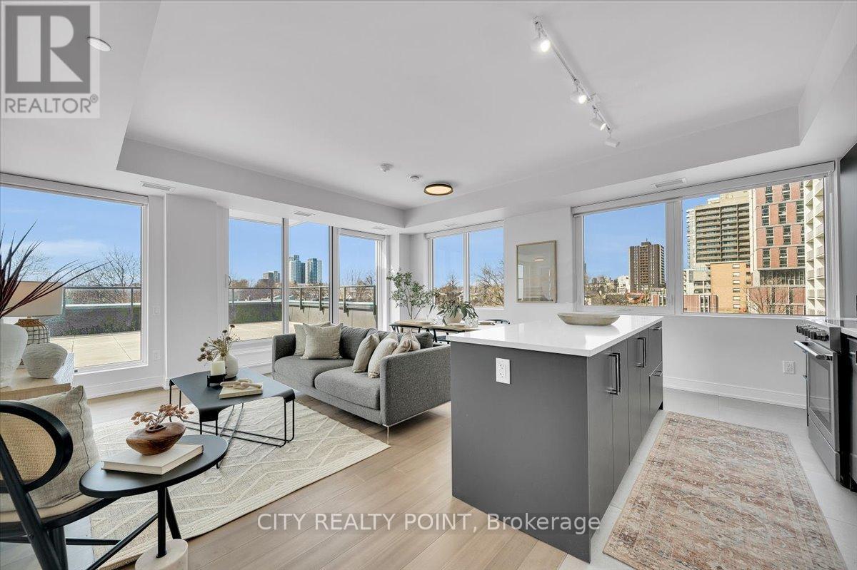 A well-lit, modern living room with a kitchen area in the background.