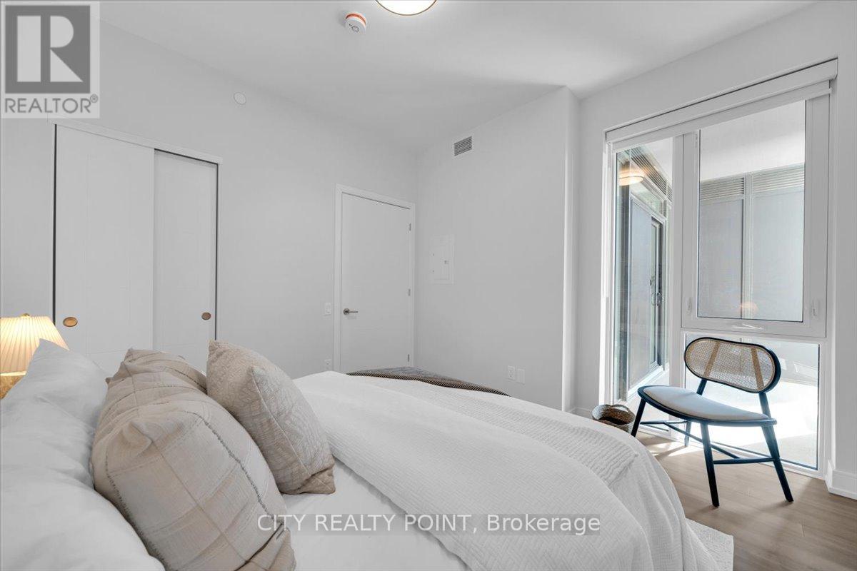 A bedroom with a bed, chair, and a window.