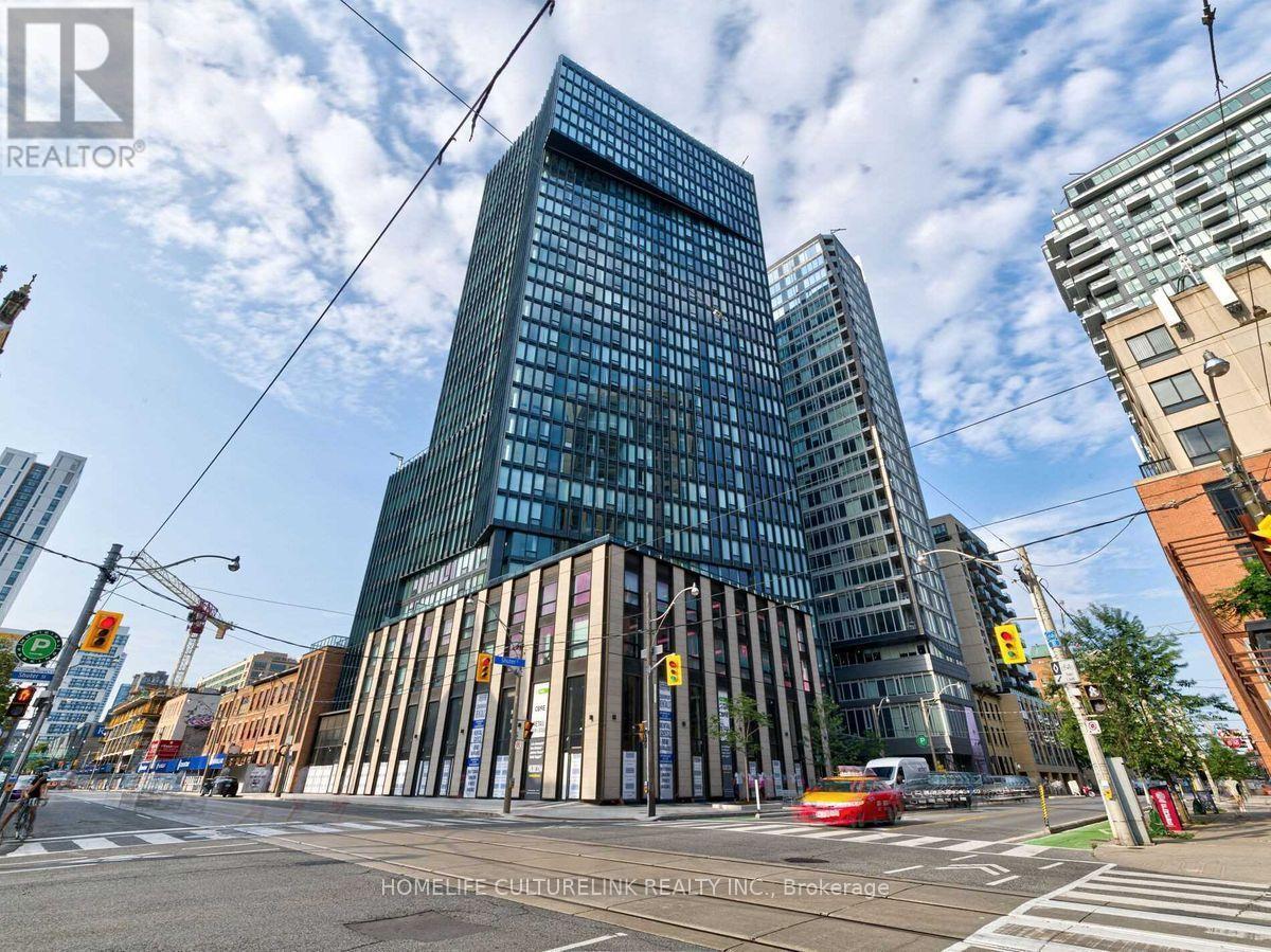 A modern glass building stands tall in a city intersection.
