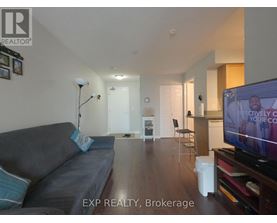 A living room with a grey couch and a television on.