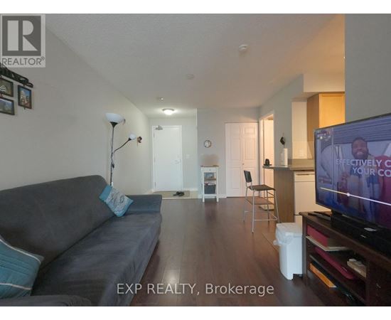 A living room with a grey couch and a television on.