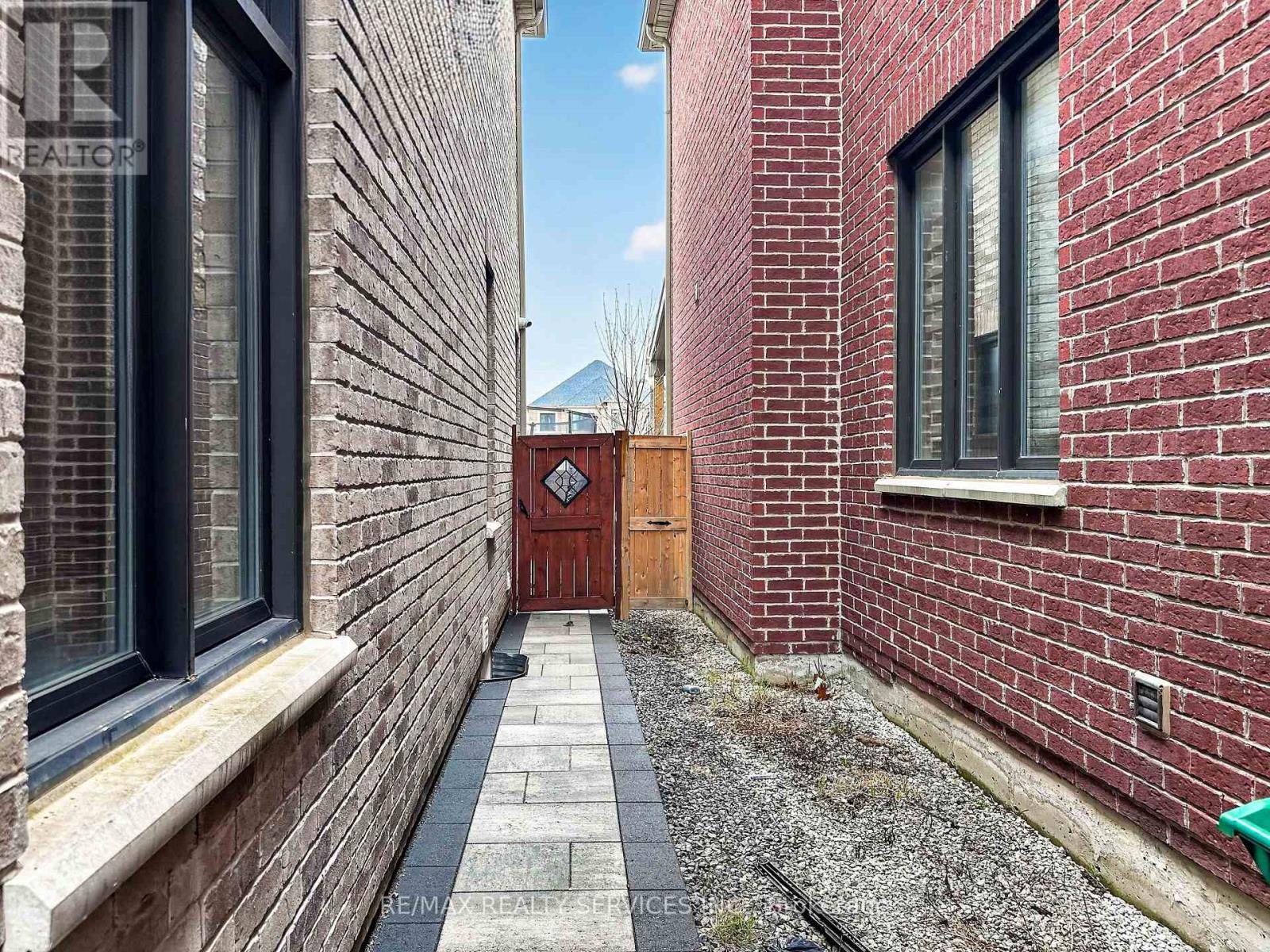 A red brick building with a wooden door at the end of a path.