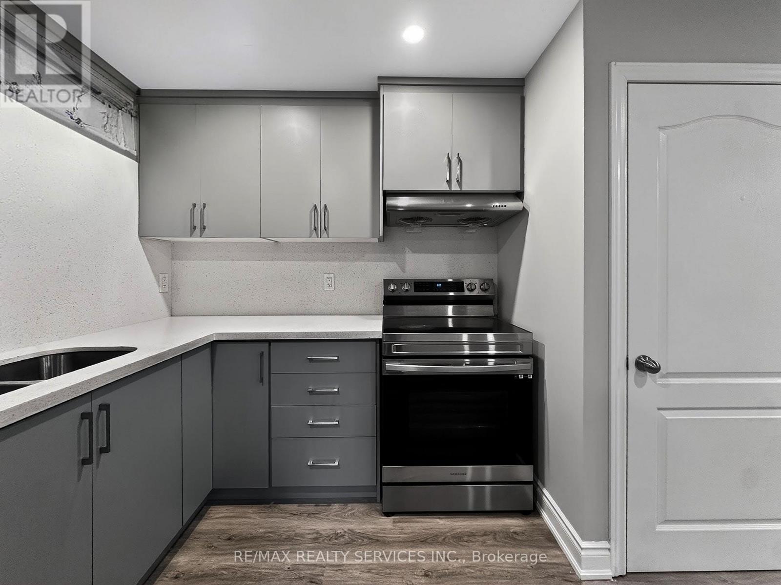 A kitchen with grey cabinets and a white door.