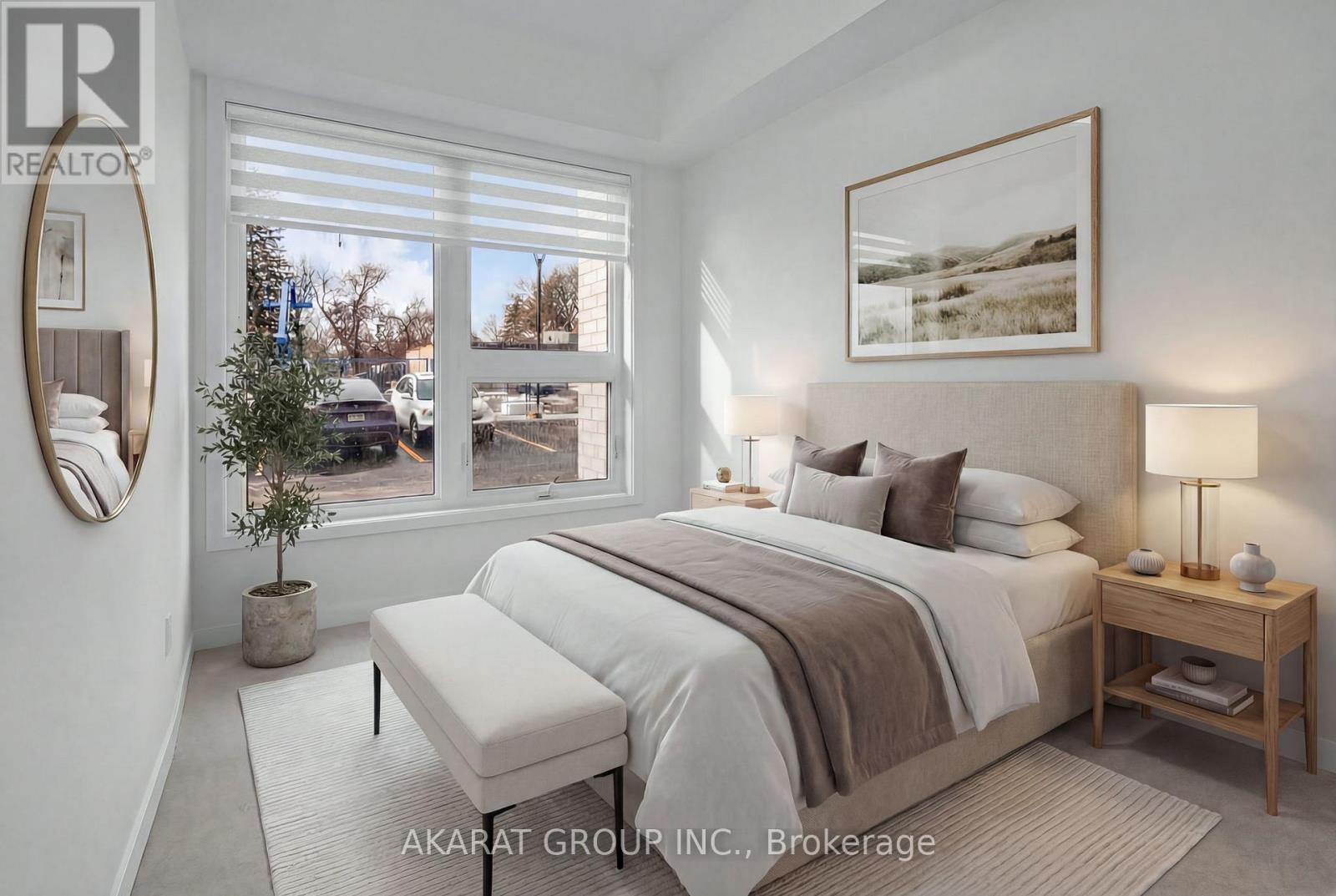 A well-lit bedroom with a large bed and a view of the outside through the window.