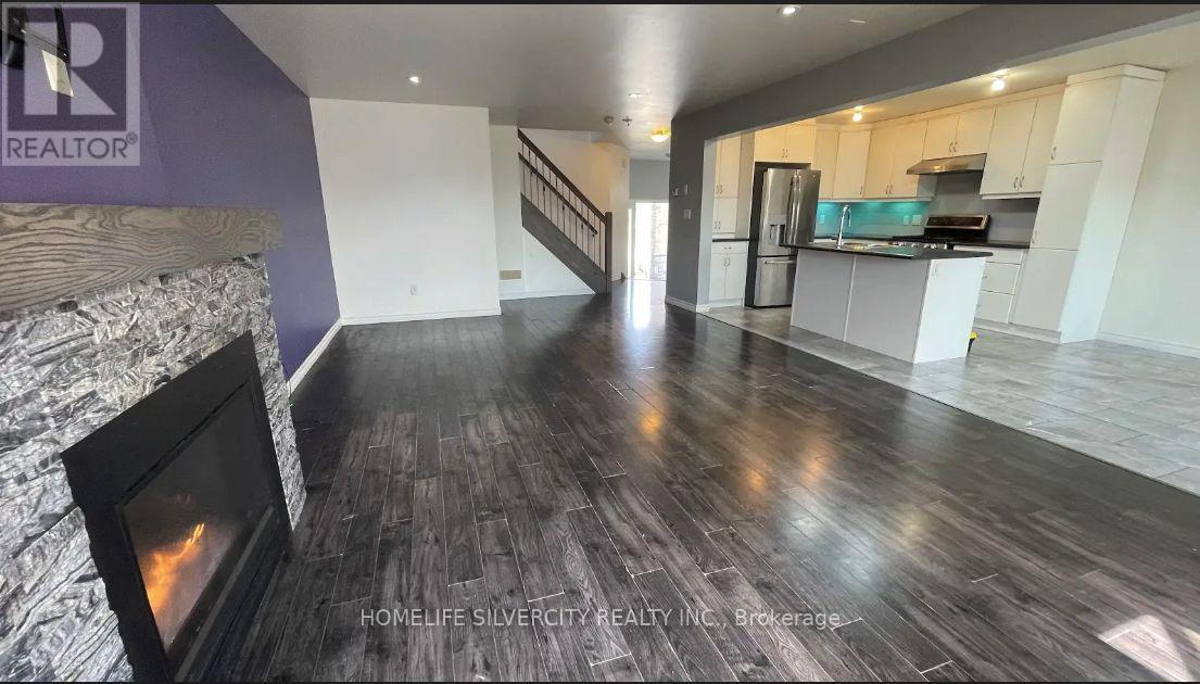 A spacious living room with a fireplace and a staircase.