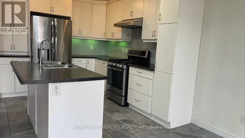 A kitchen with white cabinets and a black countertop.