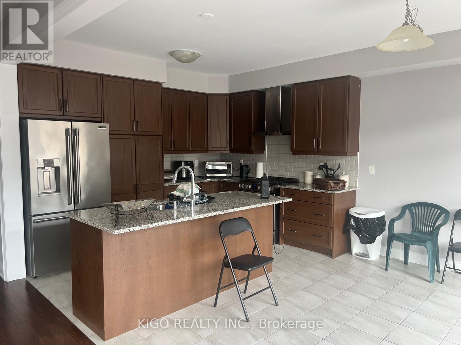 A kitchen with a refrigerator, sink, and cabinets.
