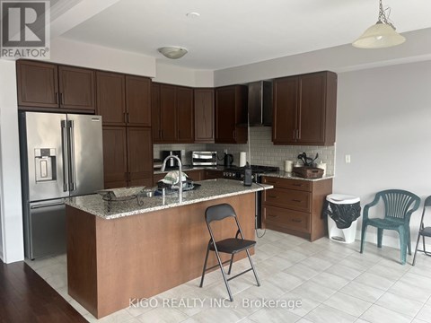 A kitchen with a refrigerator, sink, and cabinets.