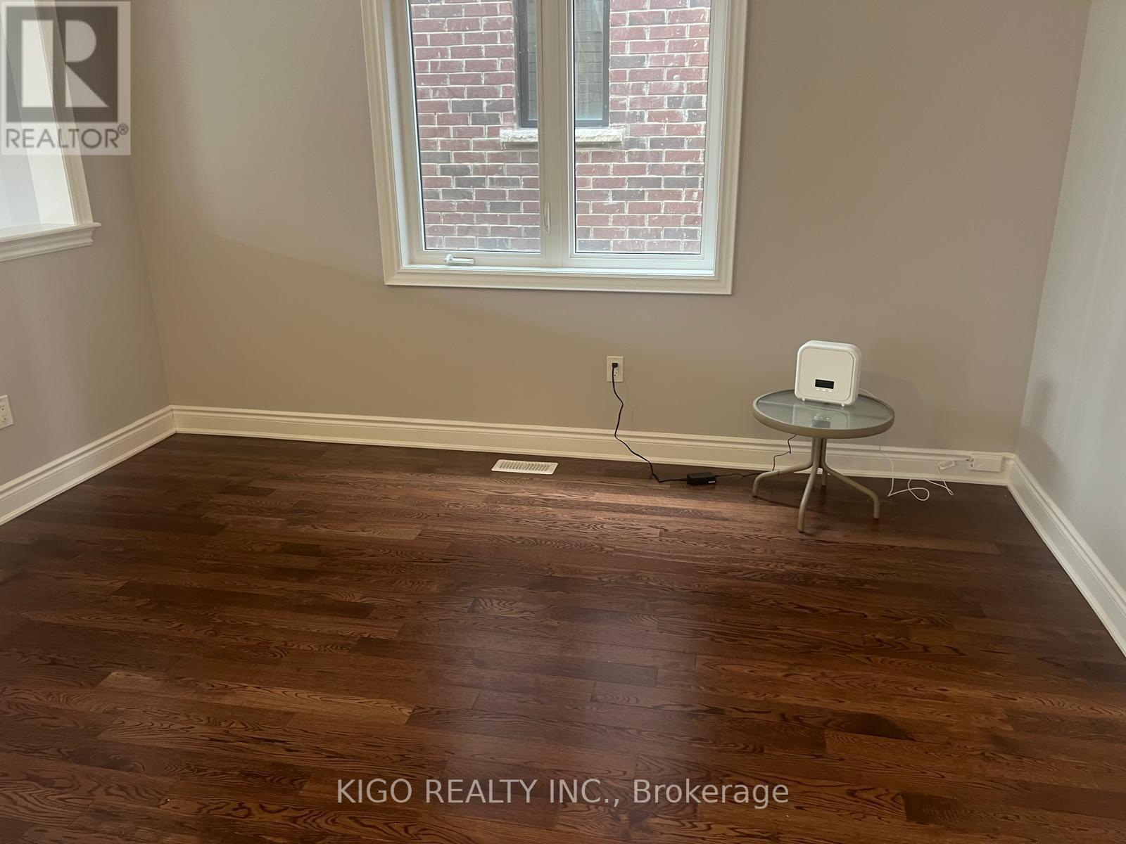 A room with a wooden floor and a white table with a lamp on it.
