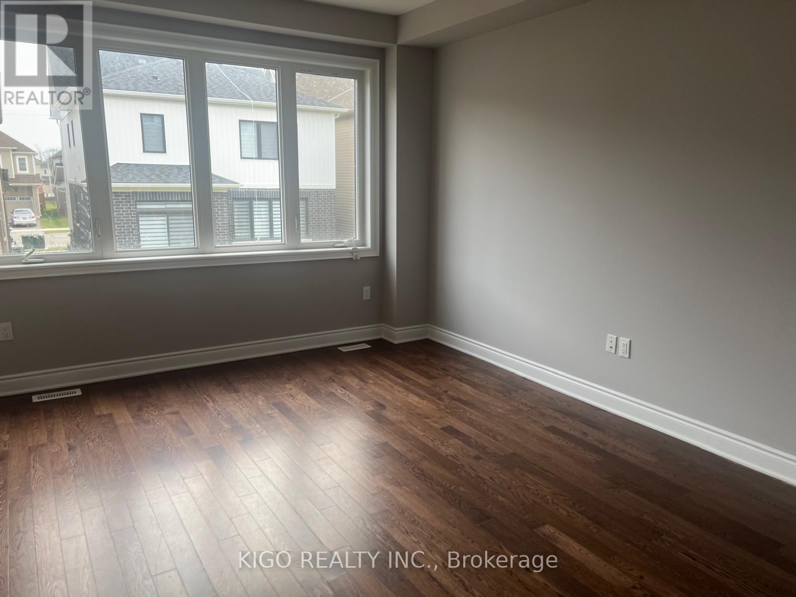 A room with wooden flooring and a large window.