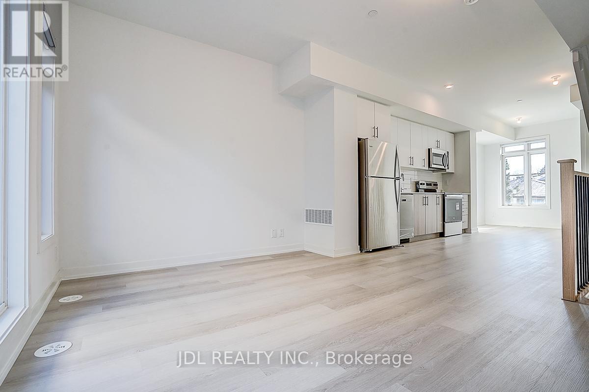 A spacious, empty room with wooden flooring and white walls.