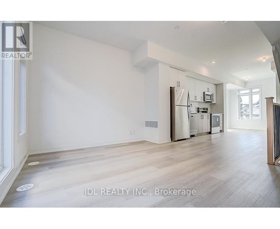A spacious, empty room with wooden flooring and white walls.
