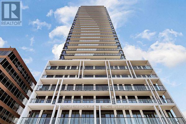 A tall building with a glass facade stands next to a shorter building with a brown facade.