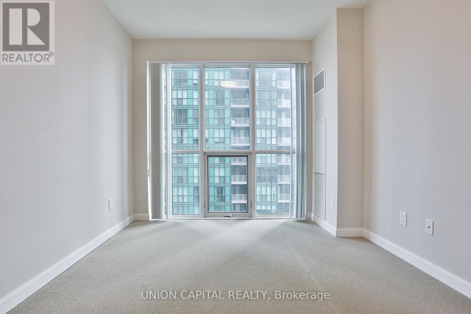 A large, empty room with a view of a building outside the window.