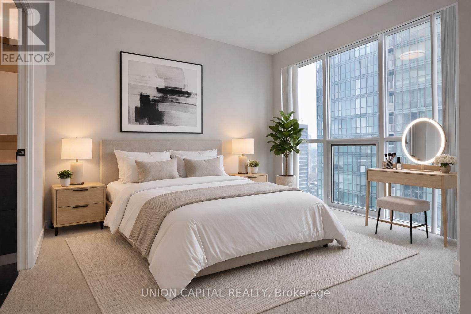 A well-lit bedroom with a large bed, a desk with a chair, and a framed picture on the wall.