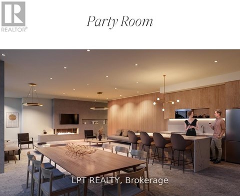 A modern party room with a long table and chairs, and two people standing by a kitchen area.
