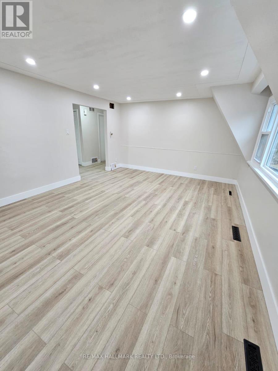 A spacious room with wooden flooring and a doorway leading to another room.