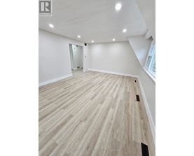 A spacious room with wooden flooring and a doorway leading to another room.