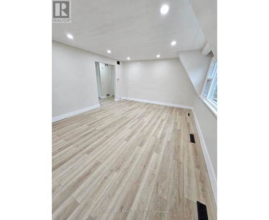A spacious room with wooden flooring and a doorway leading to another room.