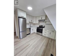 A kitchen with white cabinets and a stainless steel refrigerator.