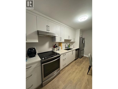 A kitchen with white cabinets and a black stove top.