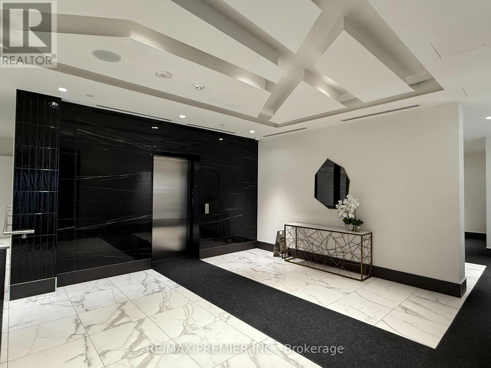 A black and white hallway with a marble floor and a mirror on the wall.