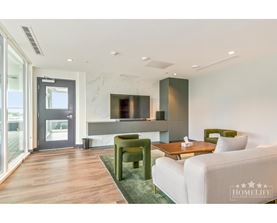 A modern living room with a white sofa, green armchair, and a wooden coffee table.