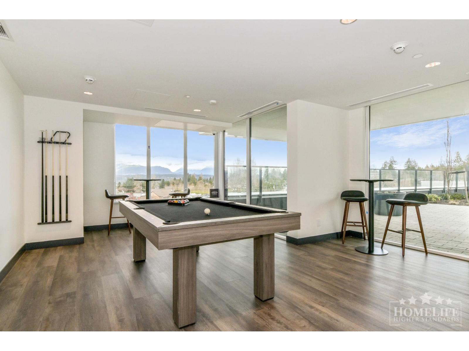 A pool table is in the middle of a room with a view of the mountains outside.