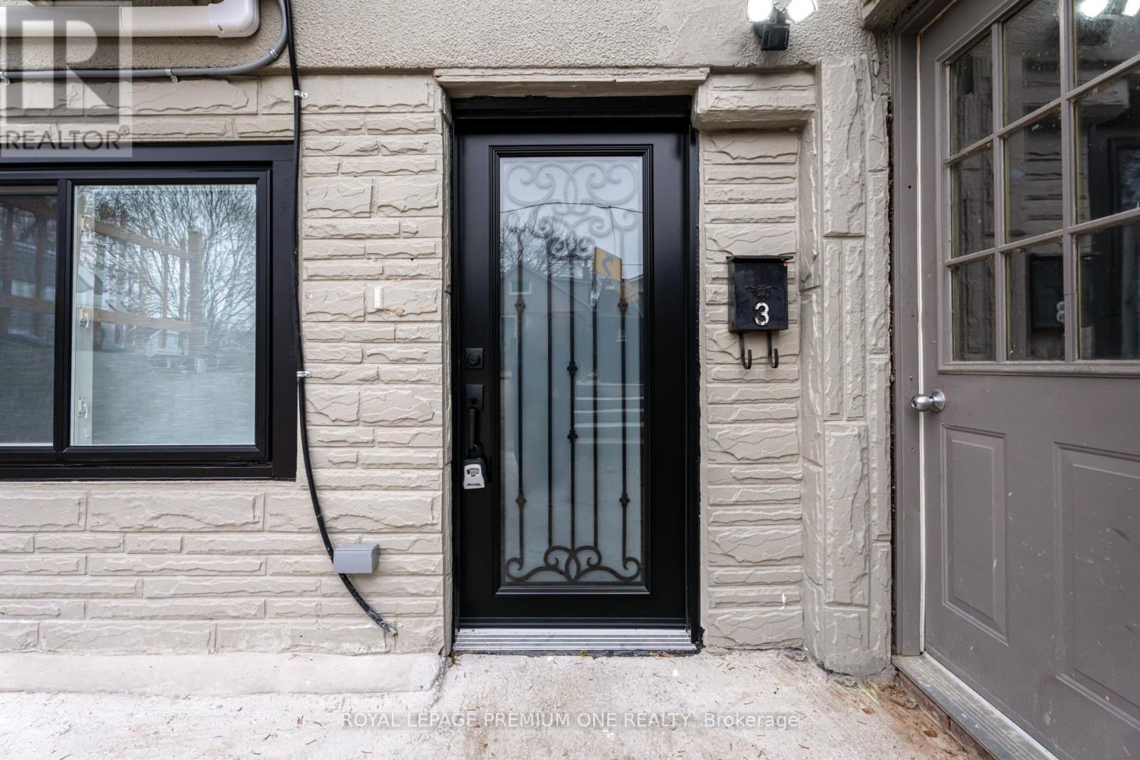 A black door with a glass panel and a metal handle is on a stone building.