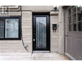 A black door with a glass panel and a metal handle is on a stone building.