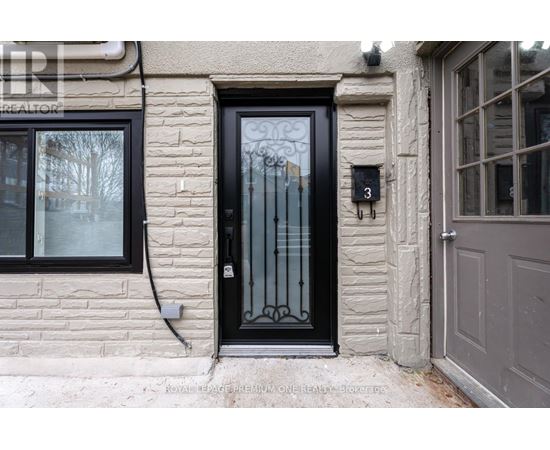 A black door with a glass panel and a metal handle is on a stone building.