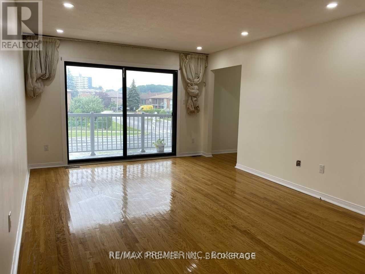 A room with wooden floors and a sliding glass door leading to a balcony.