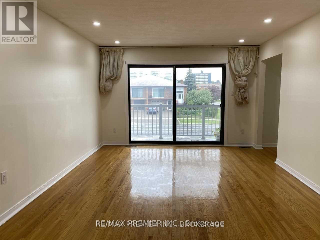 A room with wooden floors and a sliding glass door leading to a balcony.