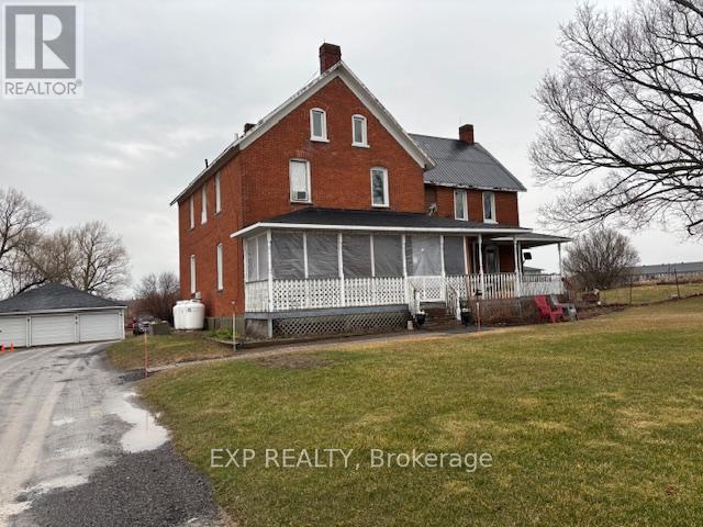 A red brick house with a white porch and a sign that says "EXP REALTY, Brokerage".