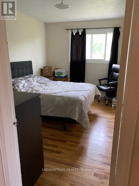 A bedroom with a bed, chair, and wooden floors.