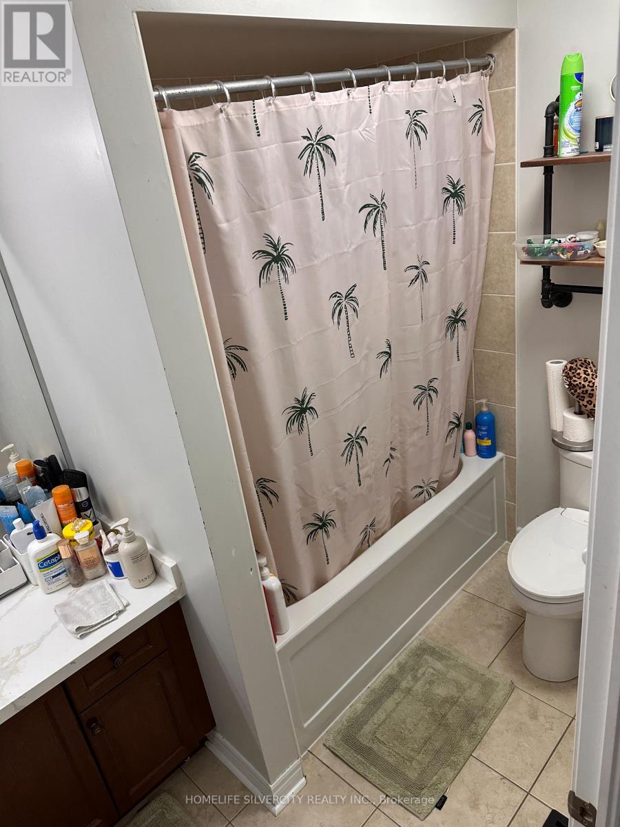 A shower with a pink curtain with palm trees on it.