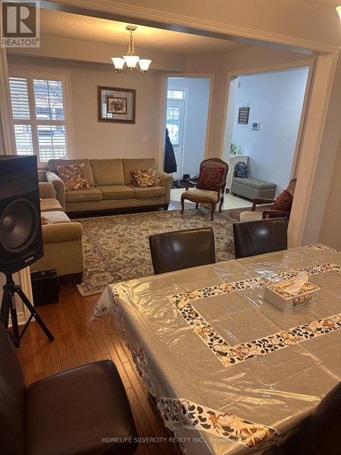 A living room with a couch, chairs, and a dining table set up with a tablecloth.
