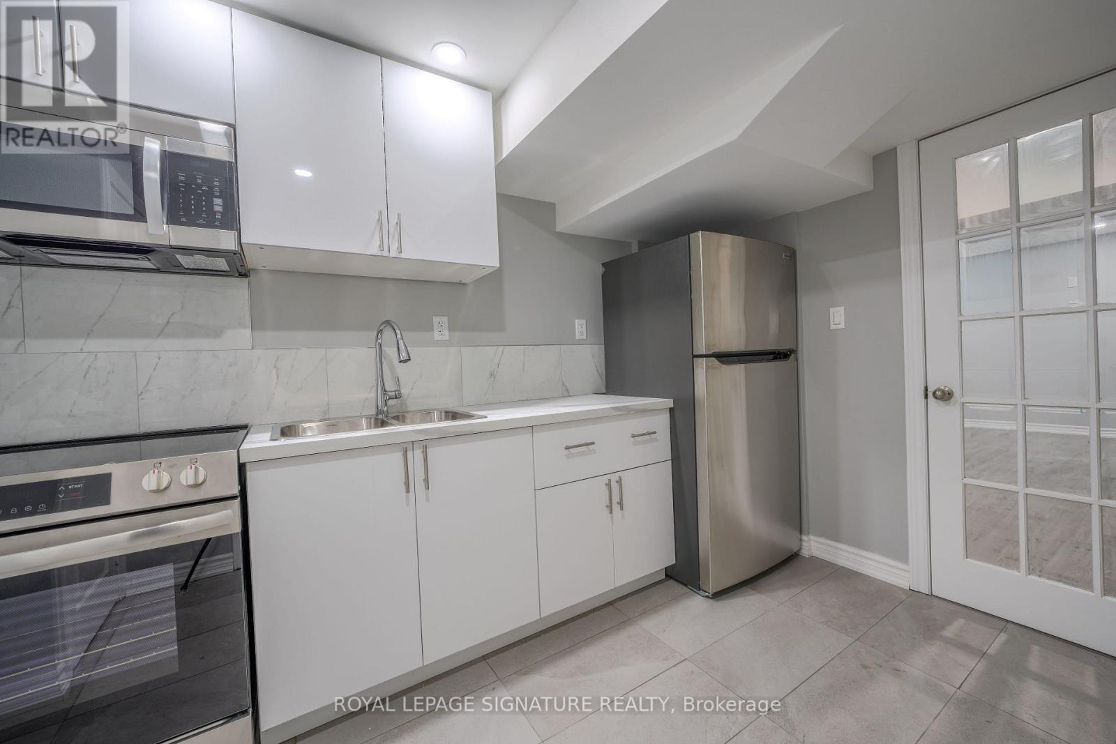 A kitchen with white cabinets and a stainless steel refrigerator.