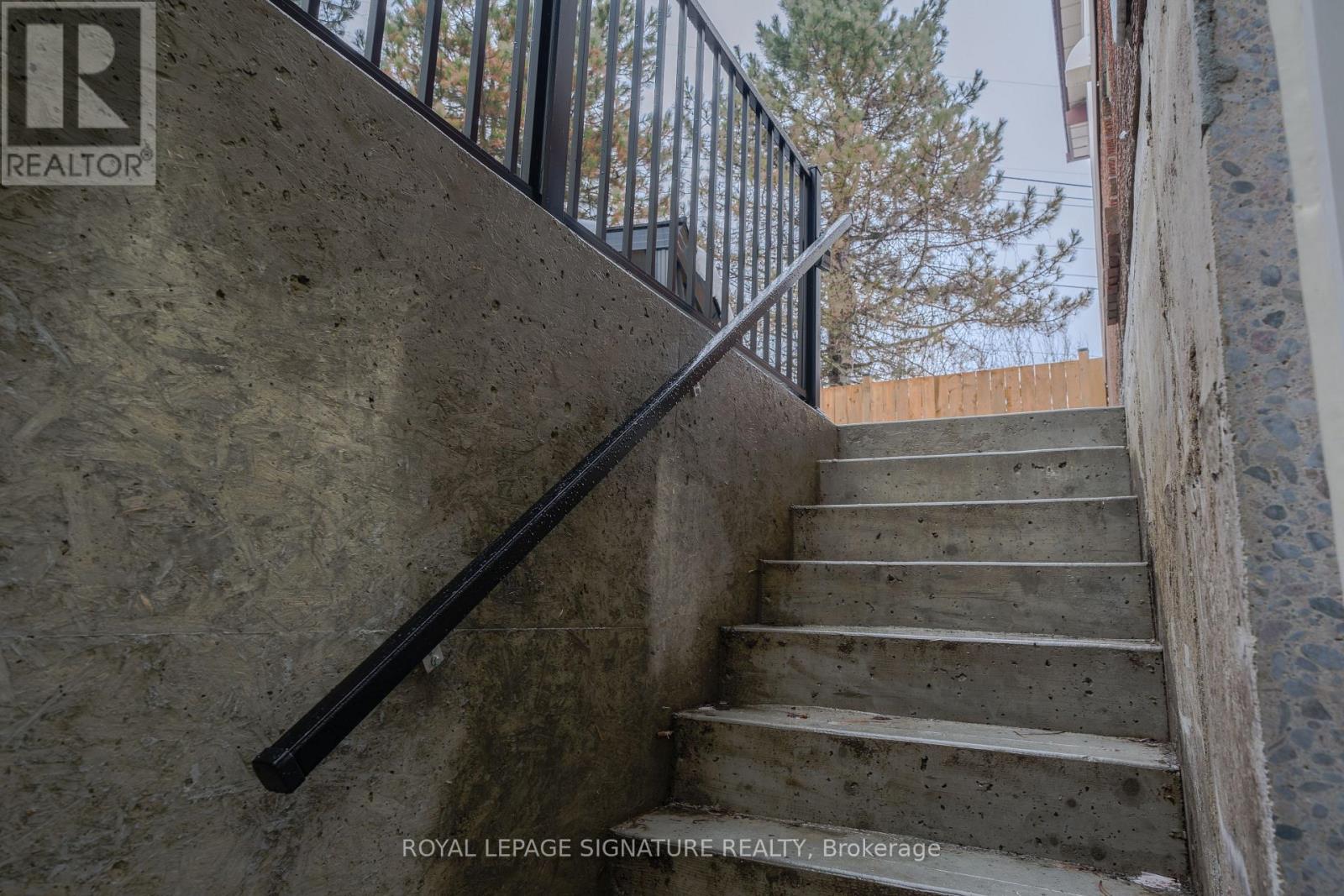 A staircase with a metal railing and a wall with a logo that says REALTOR.