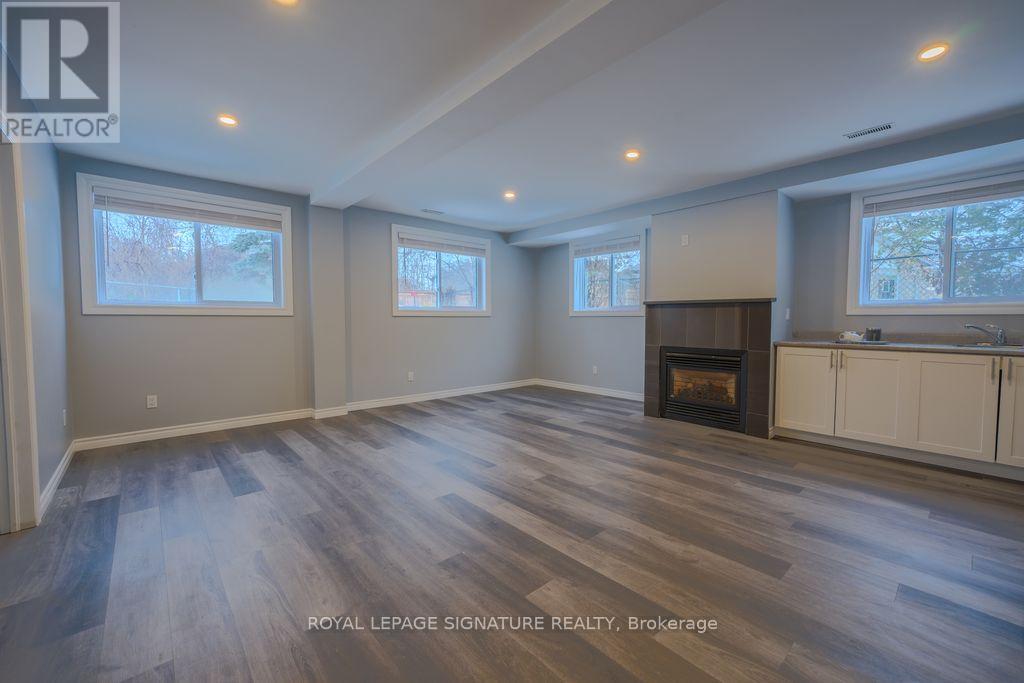 A spacious room with wooden flooring and a fireplace.