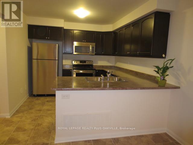 A kitchen with a refrigerator, microwave, oven, and sink.