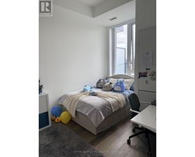 A bedroom with a bed, a chair, a desk, and a window.