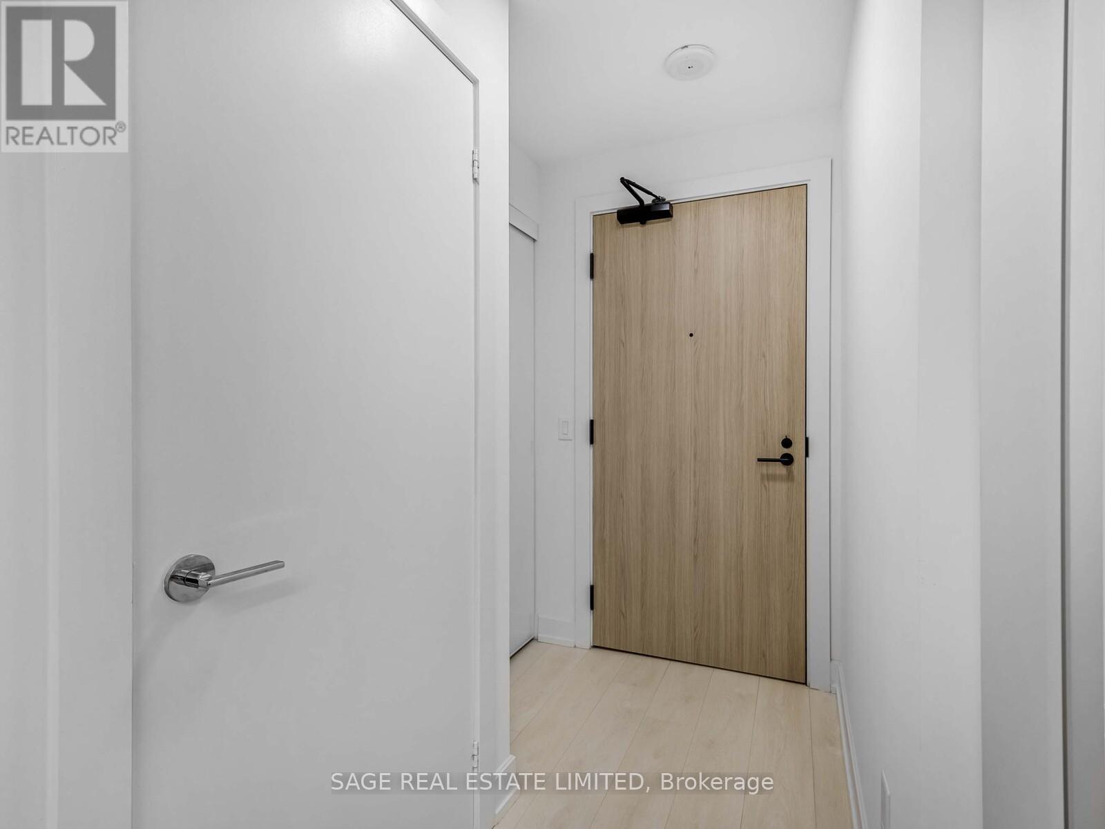 A white door with a silver handle is in a white hallway.