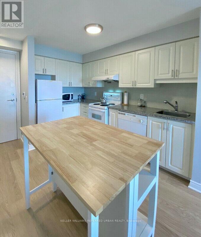 A kitchen with a table in the middle and cabinets above.