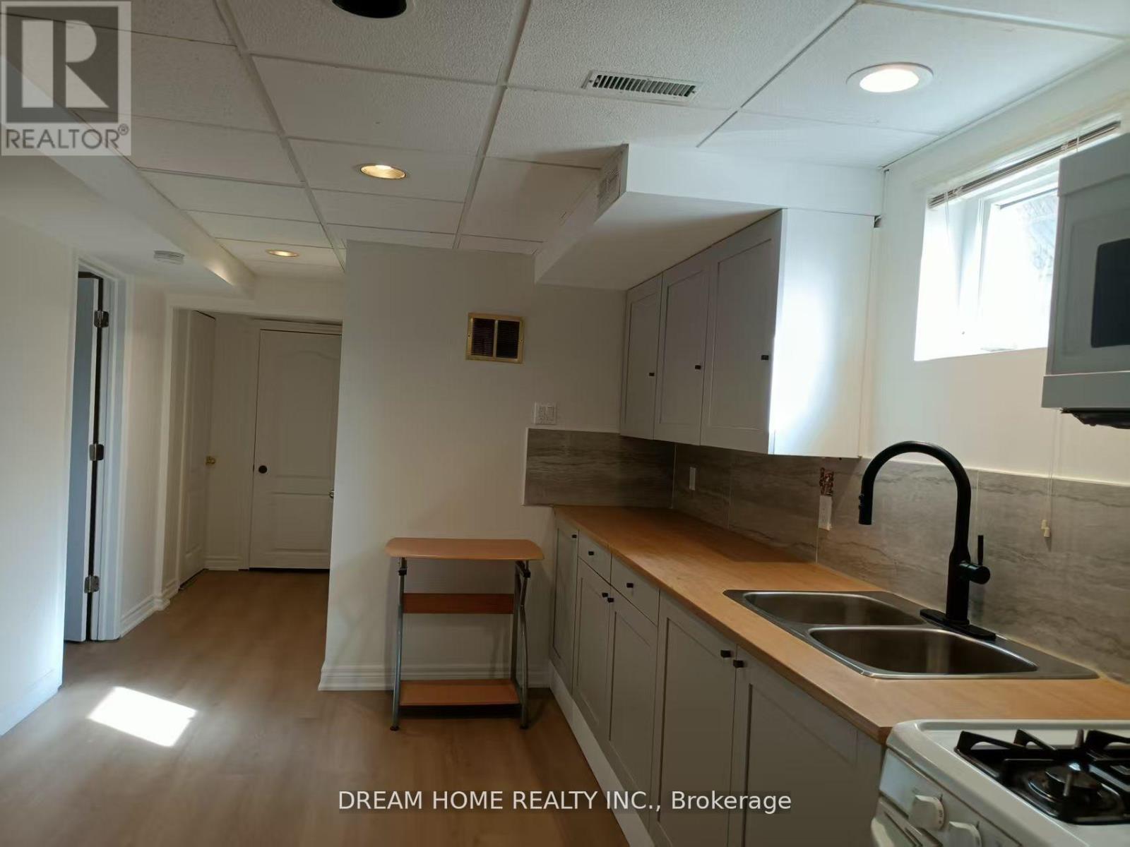 A kitchen with a stove, sink, and cabinets.