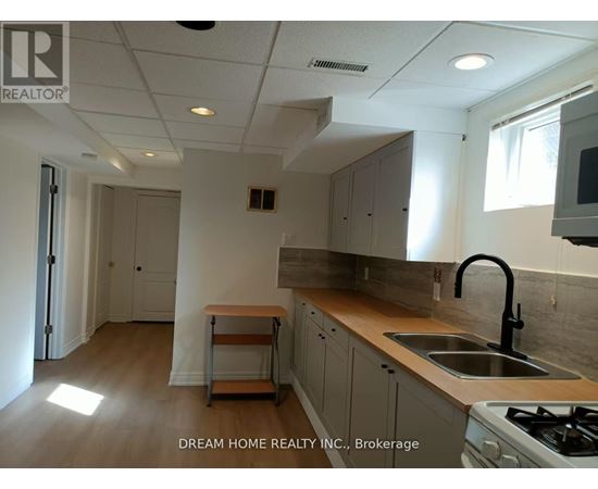 A kitchen with a stove, sink, and cabinets.